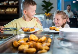 Ein Junge und ein Mädchen sitzen an einem Tisch mit Essen in der Unterkunft Hotel Grand Jasná in Demänovská Dolina + 65 Fotos