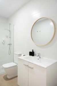 a white bathroom with a sink and a mirror at Blanq Marina Suites in Valencia