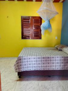 a bed in a room with a yellow wall at Dunas Bar&Hotel in Canoa Quebrada