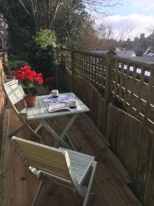a table and a chair on a wooden deck with a table and a table at Brighton Boutique Garden Studio with Free Parking in Brighton & Hove