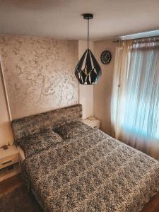 sypialnia z łóżkiem i żyrandolem w obiekcie Apartman Vila Bojana w mieście Budžak