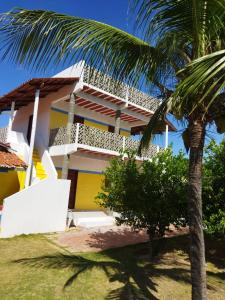 a house with a palm tree in front of it at Dunas Bar&Hotel in Canoa Quebrada