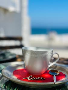 uma chávena de café num prato numa mesa em Zambujeira Lounge em Zambujeira do Mar