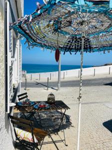 una mesa bajo una sombrilla en la playa en Zambujeira Lounge, en Zambujeira do Mar