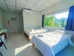 1 Schlafzimmer mit 2 Betten und einem großen Fenster in der Unterkunft Baan Mai Hom Resort Suan Phueng in Suan Phung
