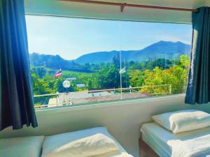 a room with two beds and a large window at Baan Mai Hom Resort Suan Phueng in Suan Phung