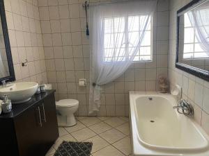 a bathroom with a tub and a toilet and a sink at Zacks Country Stay in Krugersdorp