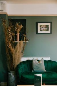 un sofá verde en la sala de estar con una almohada en The Limes Hotel en Stratford-upon-Avon