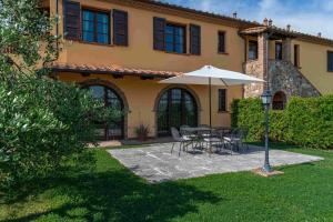 a table with an umbrella in front of a house at Agriturismo Scaforno Vacanze in Castelnuovo della Misericordia