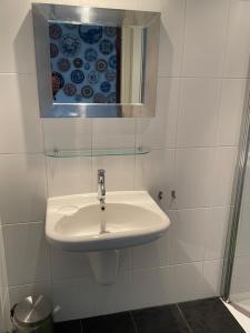 een witte badkamer met een wastafel en een spiegel bij Holiday in Spakenburg Ootje in Spakenburg