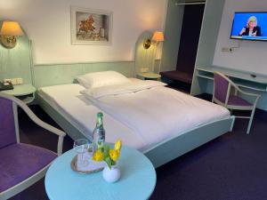 a hotel room with a bed and a table with a bottle at Hotel Weisses Lamm in Allersberg