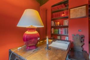 een lamp op een bureau met een boek en een kaars bij La Corte Degli Artisti by Rent All Como in Blevio