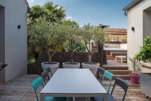 une table et des chaises blanches sur un patio arboré dans l'établissement Maison contemporaine plein centre piscine &jacuzzi, à Toulouse