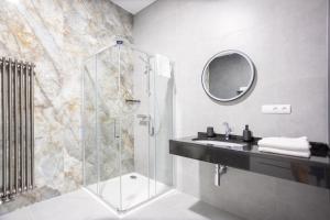 La salle de bains est pourvue d'une douche, d'un lavabo et d'un miroir. dans l'établissement Royal Apartments Liptovsky Mikulas, à Liptovský Mikuláš