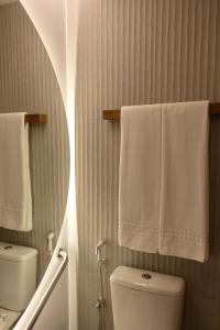 a bathroom with a white toilet and towels at Tintto Hotel in Fortaleza