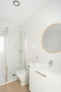 a bathroom with a toilet and a sink and a mirror at Blanq Marina Suites in Valencia