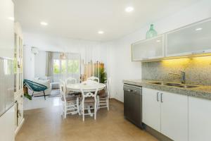 a kitchen with white cabinets and a table and chairs at Sa Figuereta Beach in Playa de Muro