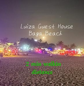 a beach at night with the words luna guest house baga beach at Luiza Guest House in Baga