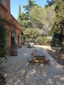 una mesa de picnic de madera en un patio de piedra en Chambres d'hôtes dans propriété rurale en Béziers