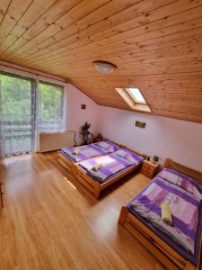 two beds in a room with a wooden ceiling at Ubytování - Černá hora II in Svoboda nad Úpou