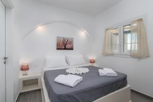 a white room with a bed with two towels on it at Sunset Village 3 in Paleochori