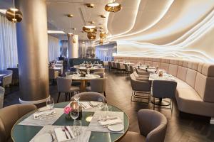 a restaurant with tables and chairs and a wall at Steigenberger Hotel Hamburg in Hamburg