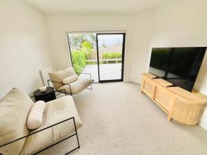 uma sala de estar com uma grande televisão de ecrã plano em Deluxe Downtown Mount Maunganui em Mount Maunganui