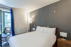 a bedroom with a bed and a chair and a window at Holborn Flat with Green Views in London