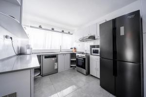 a kitchen with stainless steel appliances and a black refrigerator at Spacious 4BD House w Pool in the Heart of Herzliya by Sea N' Rent in Herzliya B