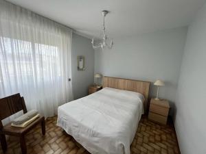 um quarto com uma cama, uma cadeira e um lustre em Appartement proche mer - Narbonne Plage 4LP2A5 em Narbonne Plage