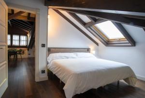 a bedroom with a large white bed with a skylight at Aticos La Riba in Luanco