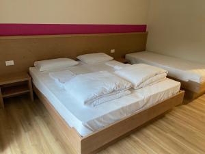 Rifugio Pian dei Ciclamini في Lusevera: سريرين في غرفة ذات أغطية ووسائد بيضاء