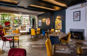 a restaurant with tables and chairs and a fireplace at Hôtel LA MARGELLE in Pernes-les-Fontaines
