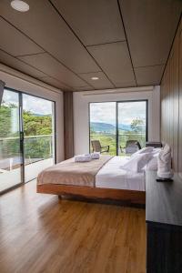 sypialnia z dużym łóżkiem i dużymi oknami w obiekcie Guayupes Hotel de Aventura w mieście Guamal