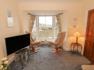 a living room with two chairs and a flat screen tv at Harlech View in Criccieth