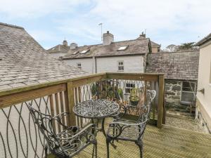 a patio with a table and chairs on a balcony at Harlech View in Criccieth