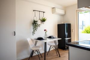 eine Küche mit einem Tisch und Stühlen in einer Küche mit einem Kühlschrank in der Unterkunft Uniklinik-Nähe Modernes Apartment, mit Balkon in Wuppertal