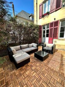 eine Terrasse mit einem Sofa, 2 Stühlen und einem Tisch in der Unterkunft Le Jardin de Léopold in Lunéville