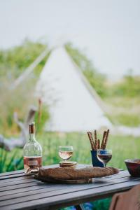 a table with a bottle and two glasses of wine at Tipi / Nature / Détente in Bragny-sur-Saône