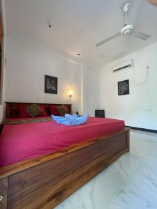 a bedroom with a large bed with pink sheets at Ubay Guest House in Trincomalee