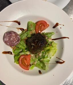 a white plate with a salad with lettuce and tomato at La renaissance in Saint-Cirgues-en-Montagne