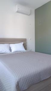 1 cama blanca grande con sábanas y almohadas blancas en Azalea Guesthouse, en Ándros