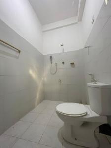 y baño blanco con aseo y ducha. en Ubay Guest House, en Trincomalee