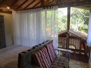 a bedroom with a bed and a couch in front of a window at Casa Carmel, Búzios in Búzios