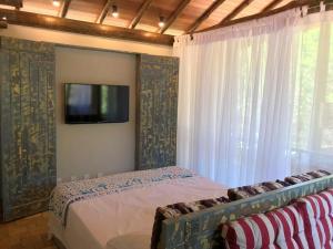 a bedroom with a bed and a tv on a wall at Casa Carmel, Búzios in Búzios