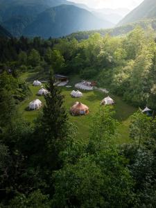 a group of tents in a field with mountains at Glamping Gozdna Jasa in Bovec