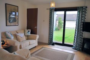 a living room with a couch and a sliding glass door at 4 Laigh Isle in Isle of Whithorn
