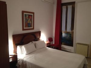 um quarto com uma cama branca e uma televisão em Hostal Absolut Stay em Barcelona