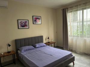 Un dormitorio con una cama con sábanas moradas y una ventana en APPARTMENT( LA PAPAYA), en La Gaulette