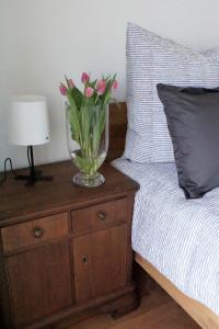 a vase with pink flowers on a night stand next to a bed at Ferienwohnung Storchennest in Bad Rothenfelde